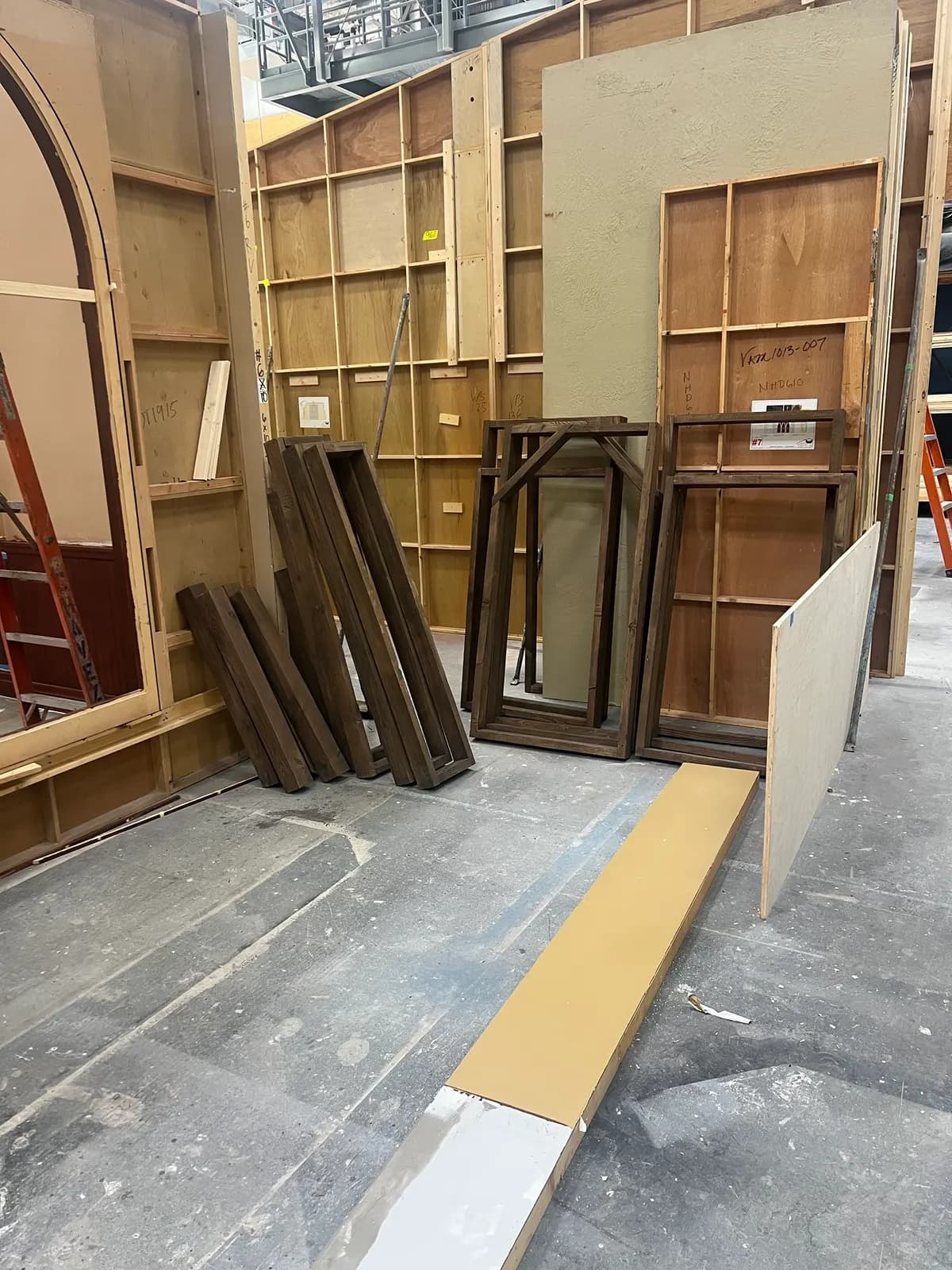 Stained bench frames and braces leaning against the shop wall