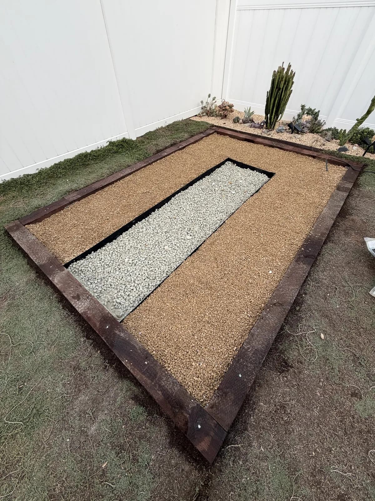 The finished floor: a pale gravel walkway down the center, edged in black steel, with tan pea gravel on either side