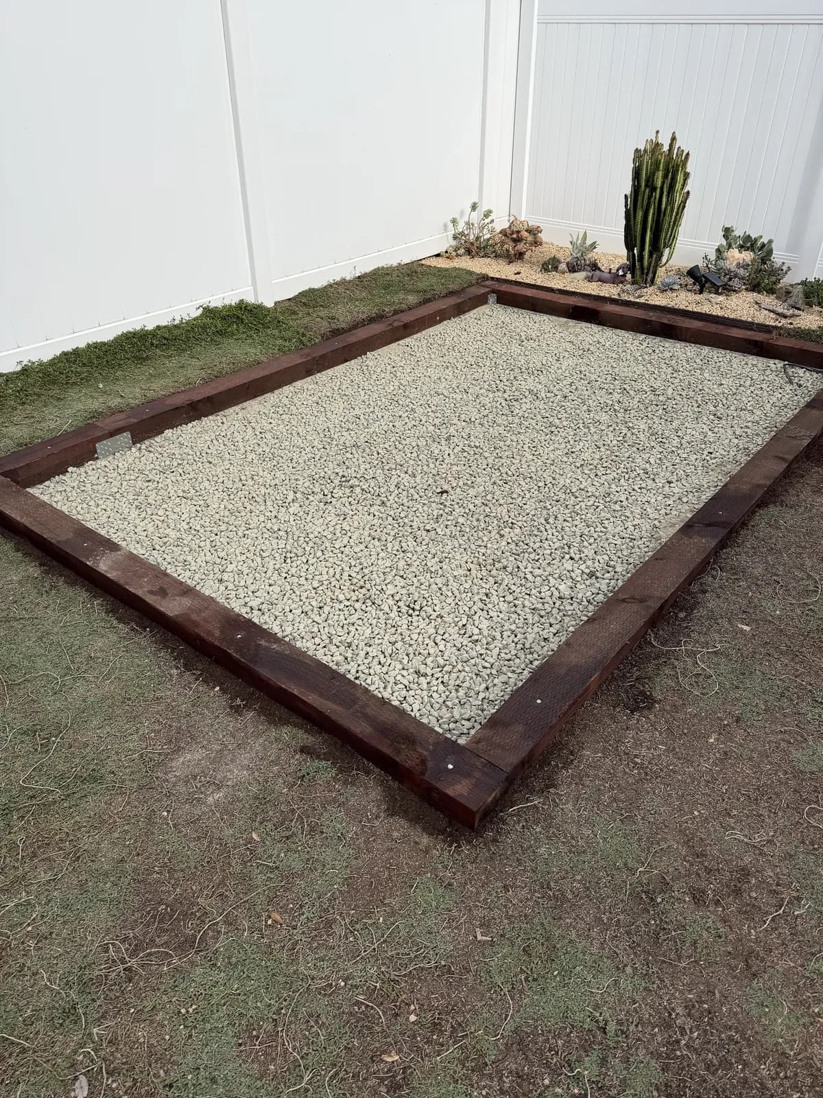 The timber frame filled edge to edge with pale crushed gravel, bolt heads flush along the timbers
