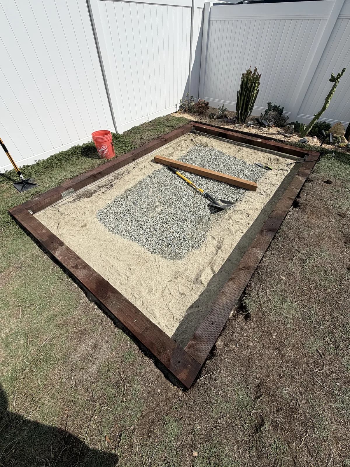 The finished 6×6 frame set on the sand bed, nail plates at the corners and gravel showing in the middle